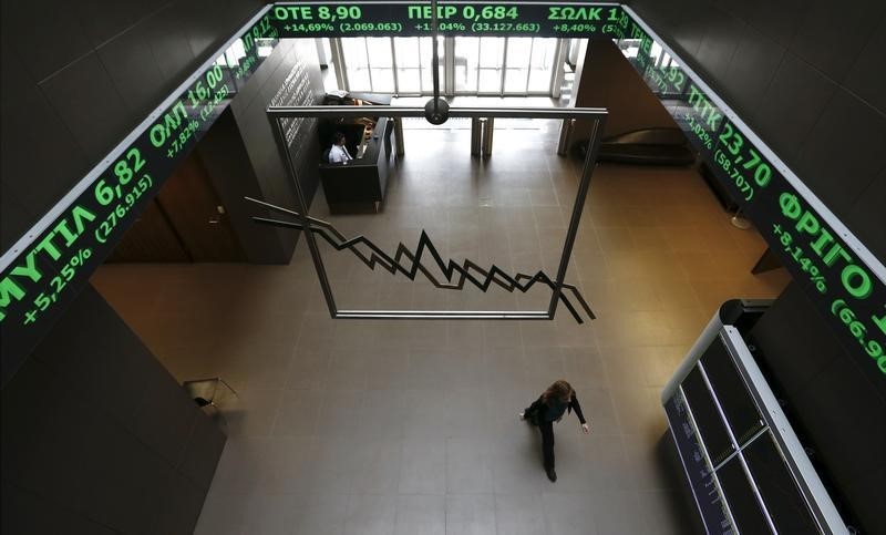 © Reuters. A woman walks inside the Athens stock exchange as a stock ticker shows stock options making major gains, inside the Athens stock exchange building