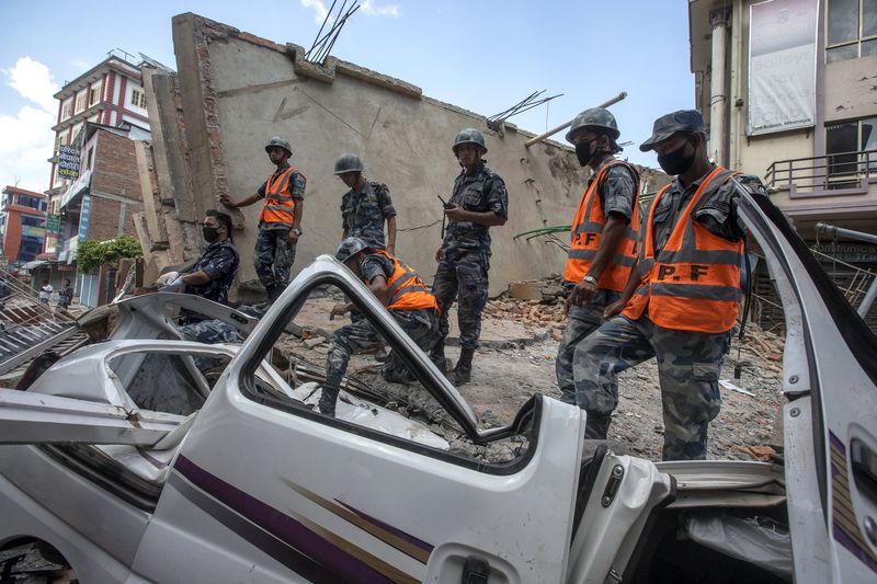 © Reuters. Nepalese military personnel stands on a collapsed building after earthquake in centre of Kathmandu