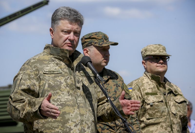 © Reuters. Ukrainian President Petro Poroshenko (L) delivers a speech as he visits an army training centre in Chernihiv region, Ukraine