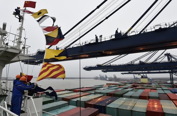 © Reuters. Crew members attach flags as the largest container ship in world, CSCL Globe, docks during its maiden voyage, at the port of Felixstowe in south east England