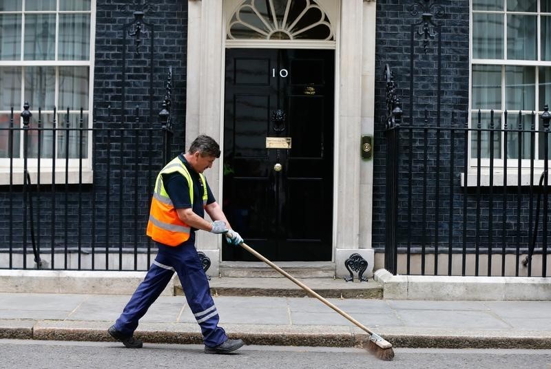 © Reuters. A municipal employee sweeps the road outside 10 Downing Street ahead of Britain's Prime Minister David Cameron's first cabinet meeting, in Westminster, London