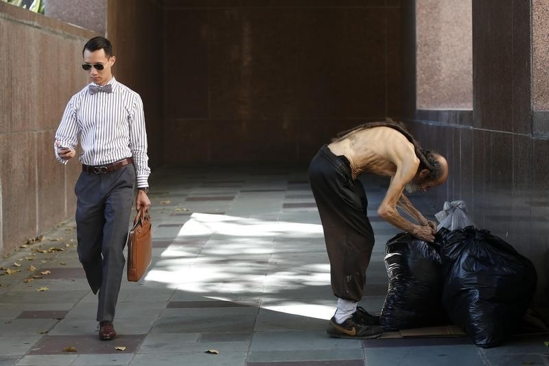 © Reuters. A man looks at his phone as he walks out of courthouse past man arranging bags in Los Angeles