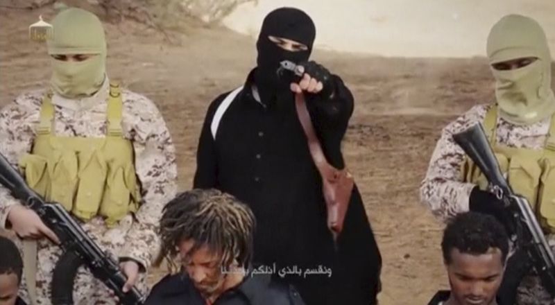 © Reuters. An Islamic State militant holds a gun while standing behind what are said to be Ethiopian Christians in Wilayat Fazzan, in this still image from an undated video made available on a social media website