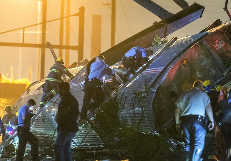 © Reuters. Rescue workers climb into the wreckage of a derailed Amtrak train to search for victims in Philadelphia