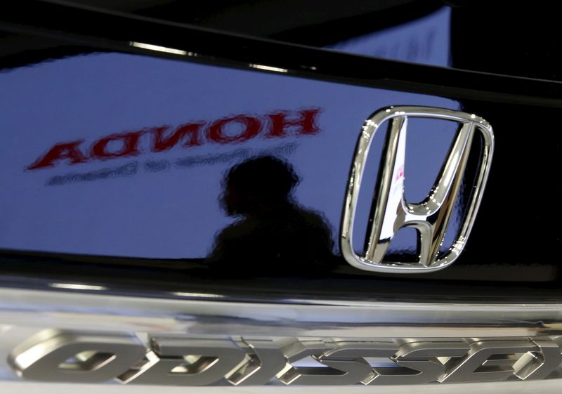 © Reuters. File photo of a visitor and a logo of Honda Motor reflected on a Honda Odyssey car at the company showroom in Tokyo