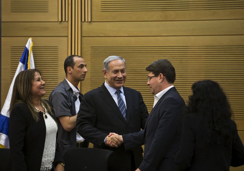 © Reuters. Israel's Prime Minister Netanyahu shakes hands with lawmaker Akunis in Jerusalem