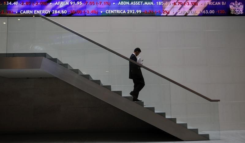 © Reuters. A man walks down steps under a share price ticker at the London Stock Exchange in the City of London