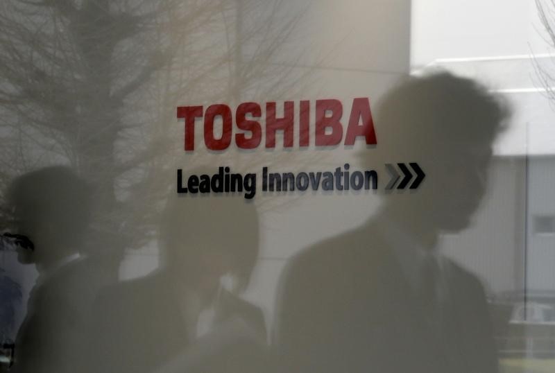 © Reuters. Logo of Toshiba Corp is seen as people are reflected on a window at the company's Hydrogen Energy R&D Center after its opening ceremony in Tokyo