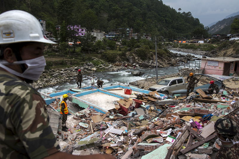 © Reuters. Militares nepaleses procuram corpos em meio a detroços de prédios destruídos por terremoto no vilarejo de Singati