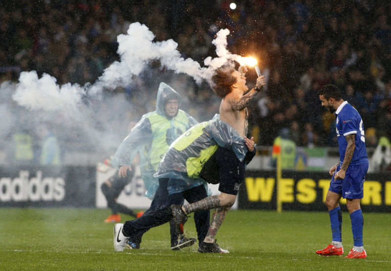 © Reuters. A security attempts to stop a supporter of Dnipro Dnipropetrovsk who celebrates the victory over Napoli in the Europa League semi-final second leg soccer match at the Olympic stadium in Kiev