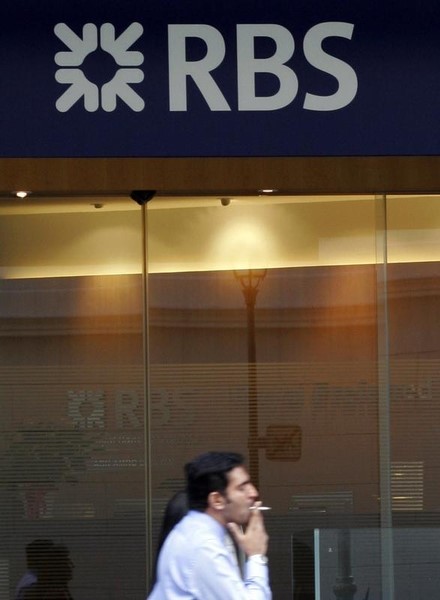 © Reuters. A man smokes as he walks past a Royal Bank of Scotland branch in Singapore's financial district