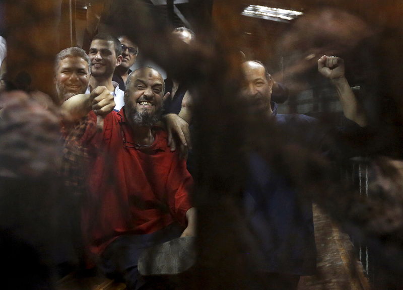 © Reuters. Muslim Brotherhood's senior member Mohamed El-Beltagy reacts as he sits behind bars with other Muslim Brotherhood members at a court in the outskirts of Cairo