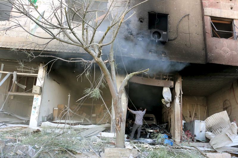 © Reuters. A man inspects a damaged site after what activists said were airstrikes by forces loyal to Syria's President Bashar al-Assad in the Damascus suburb of Ain Tarma