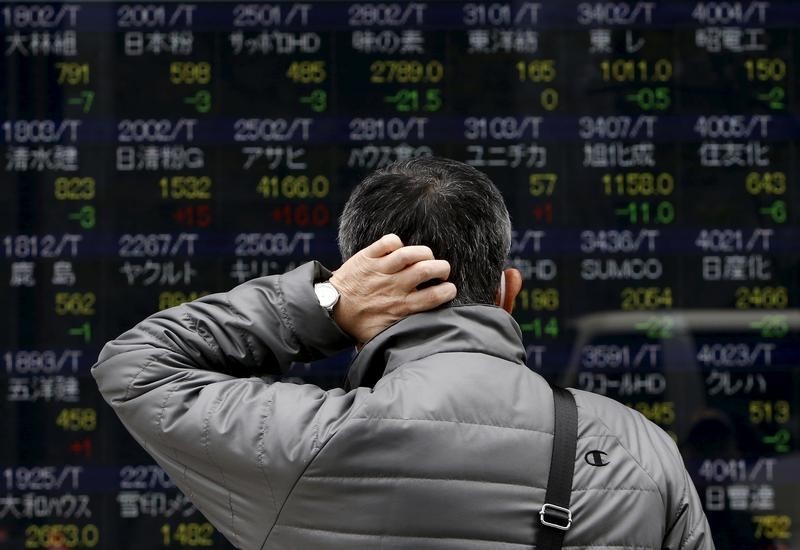 © Reuters. A pedestrian scratching his head looks at an electronic board showing the various stock prices outside a brokerage in Tokyo