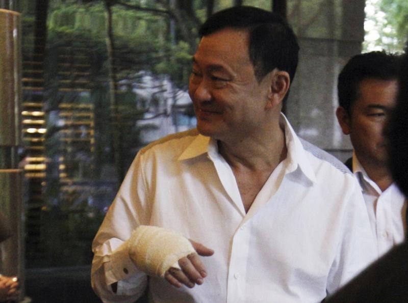 © Reuters. Thailand's former prime minister Thaksin Shinawatra sports a bandaged hand as he leaves a meeting at a hotel in Singapore