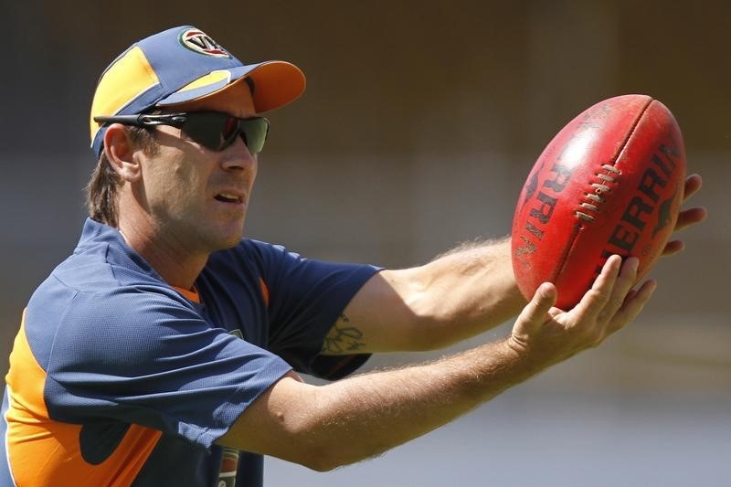 © Reuters. Langer plays with a rugby ball during a cricket practice session in Ahmedabad