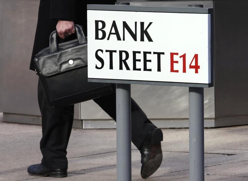 © Reuters. A worker passes a sign for Bank Street in the Canary Wharf financial district in London