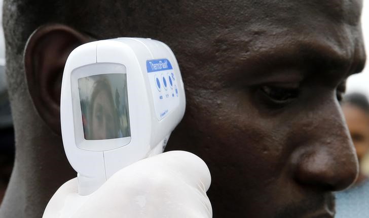 © Reuters. Trabalhador social medindo temperatura de homem na Guiné