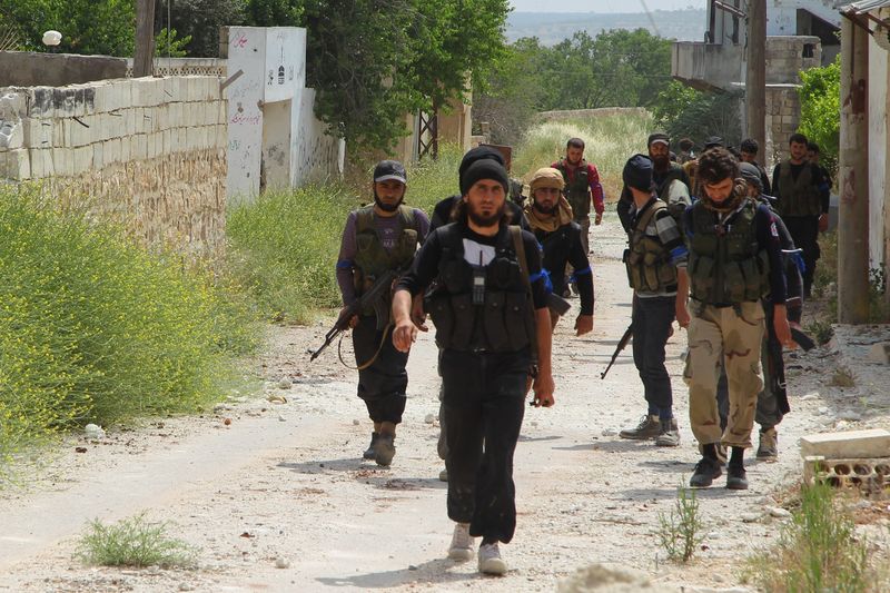 © Reuters. Rebel fighters walk in Mastouma village in Idlib city