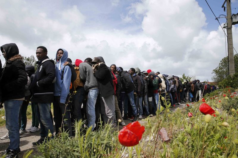 © Reuters. Dozens of migrants queue for the distribution of their daily meal in Calais