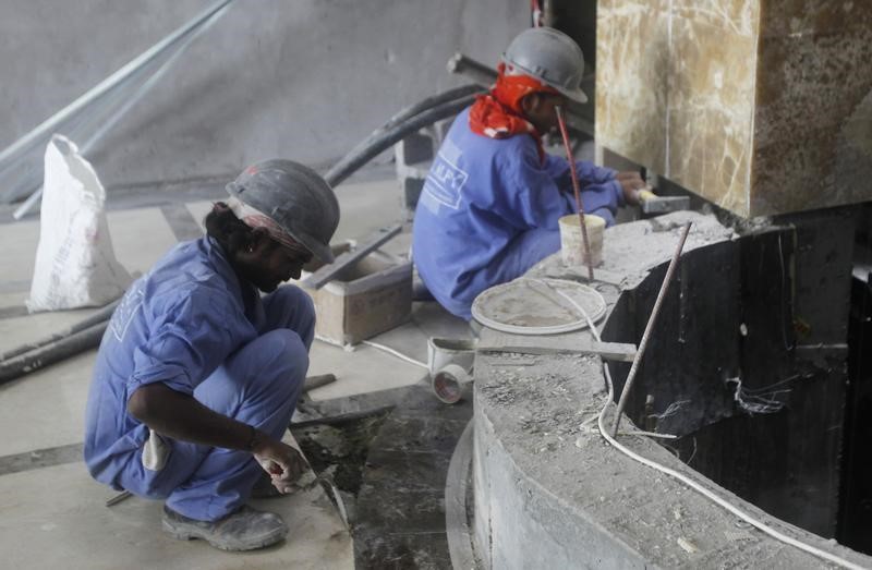 © Reuters. Labourers work at a construction site in Doha