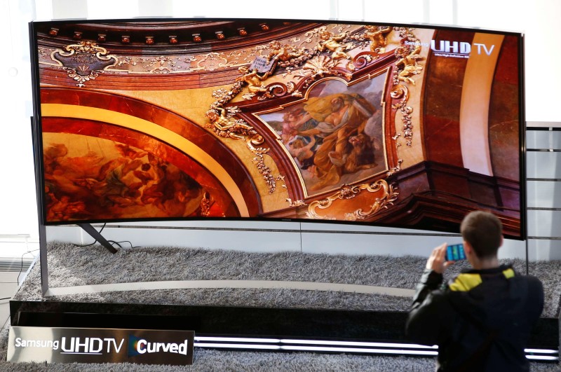 © Reuters. A visitor takes photographs of a Samsung Electronics' 105-inch Curved Ultra High Definition TV at the company's headquarters in Seoul