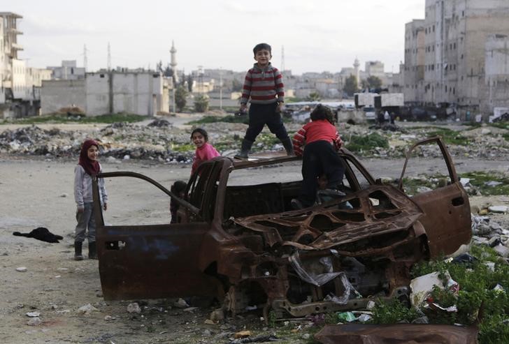 © Reuters. Crianças brincam nos restos de um carro queimado em Aleppo