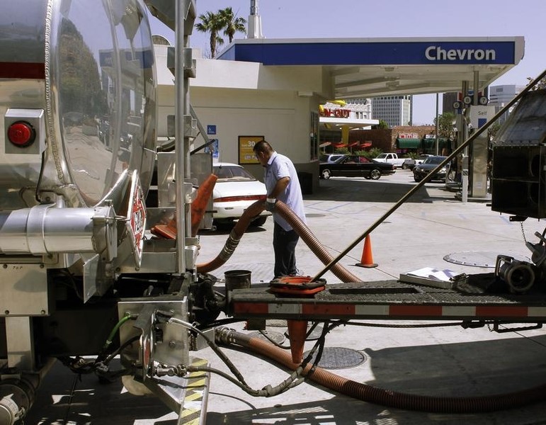 © Reuters. A gasoline tanker driver moves a hose as he fills tanks at a Chevron petrol station in Los Angeles, California