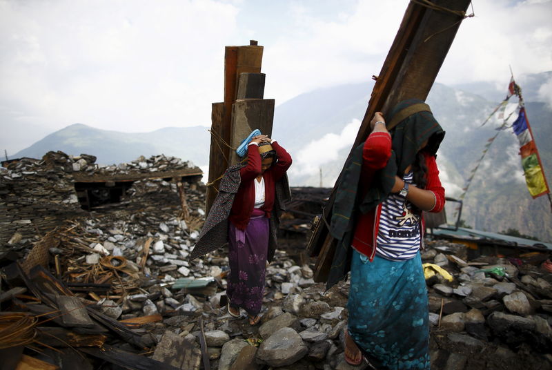 © Reuters. Earthquake victims carry wood recovered from a collapsed house at Barpak village at the epicenter of the April 25 earthquake in Gorkha district