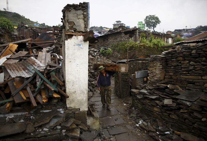 © Reuters. Vítima do terremoto carregando pedaços de madeira nos escombros de uma casa no vilarejo de Barpak