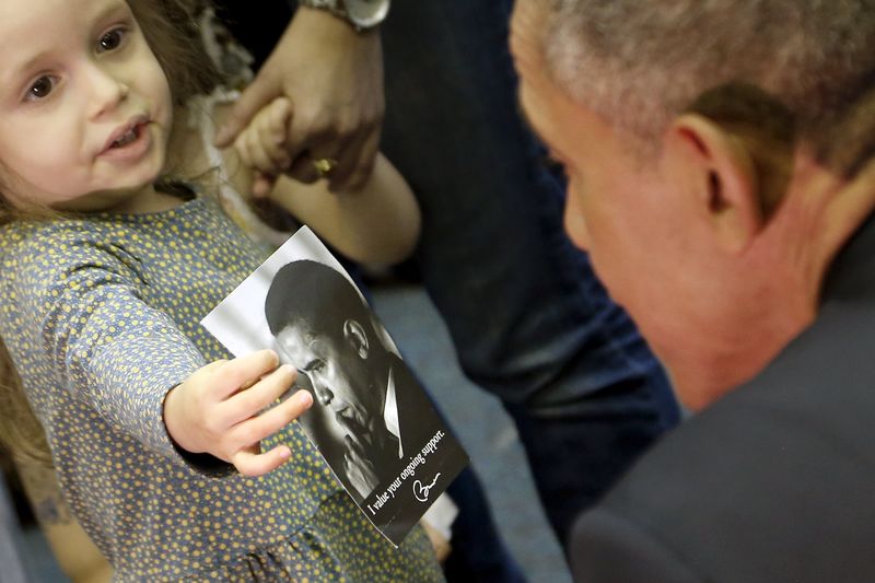 © Reuters. A girl shows U.S. President Obama a picture of himself as he visits her classroom after his remarks on Jewish American History Month at the Adas Israel Congregation synagogue in Washington