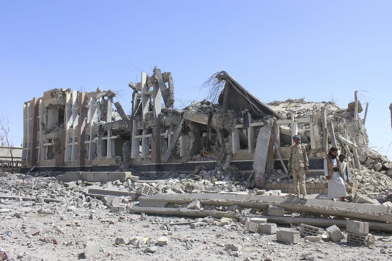 © Reuters. Houthi militants stand near a government building destroyed by a Saudi-led air strike in Yemen's northwestern city of Saada