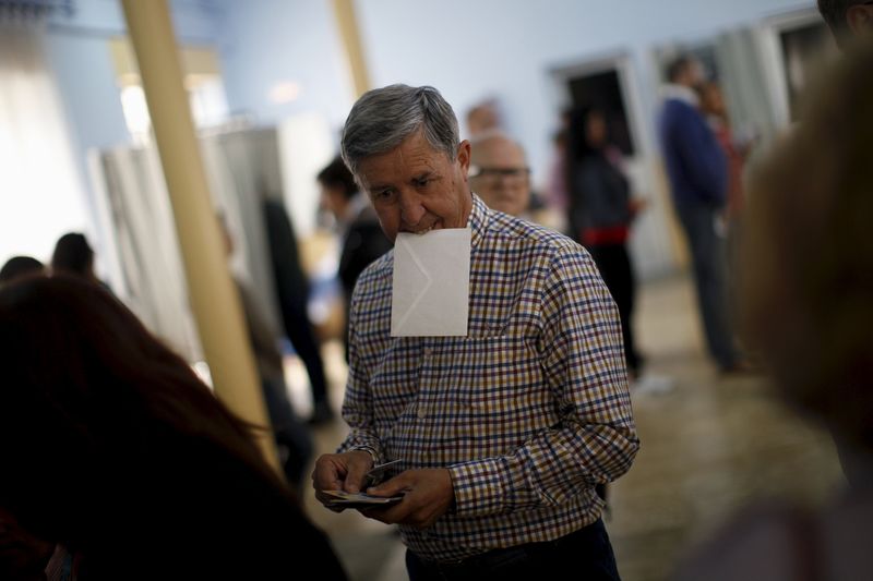 © Reuters. Homem segurando cédula com a boca antes de votar, na Espanha