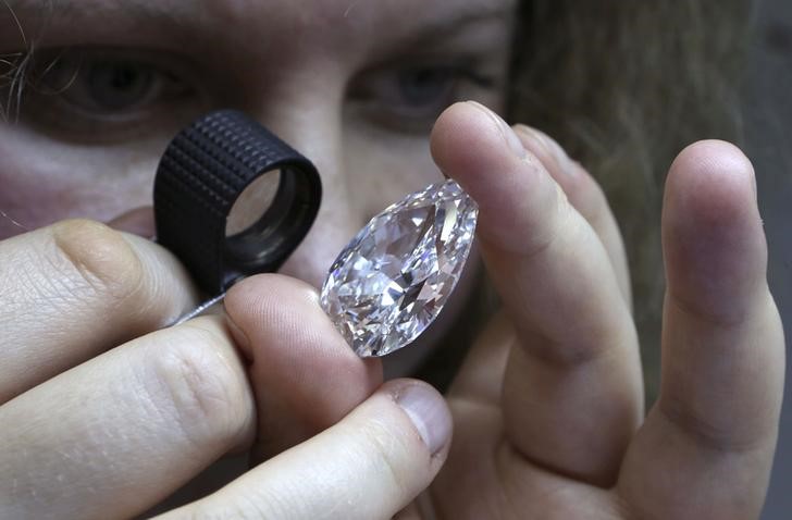 © Reuters. Женщина изучает алмаз в офисе компании, принадлежащей Алросе, в Москве