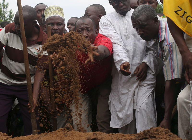 © Reuters. Homem joga terra sobre o corpo de líder oposicionista Zedi Feruzi durante seu enterro em Bujumbura