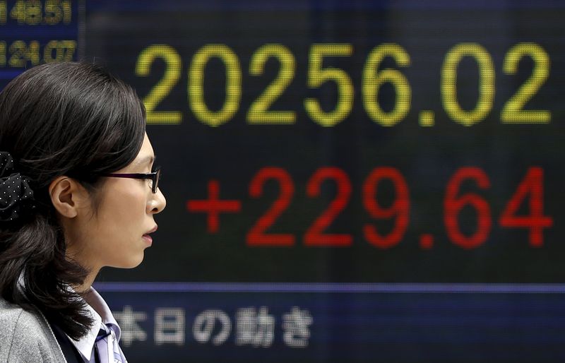 © Reuters. A pedestrian walks past an electronic board showing the Japan's Nikkei average outside a brokerage in Tokyo