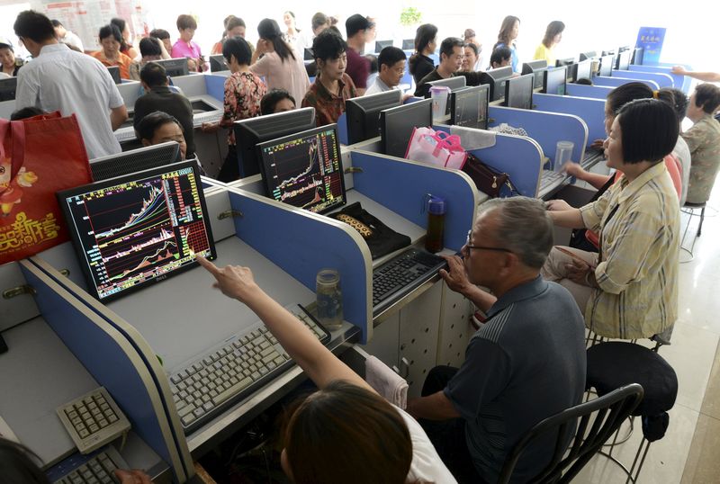 © Reuters. Investors look at computer screens showing stock information at a brokerage house in Fuyang