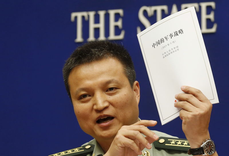 © Reuters. Spokesperson of Chinese Ministry of National Defense Senior Colonel Yang holds a copy of the annual white paper on China's military strategy during a news conference in Beijing