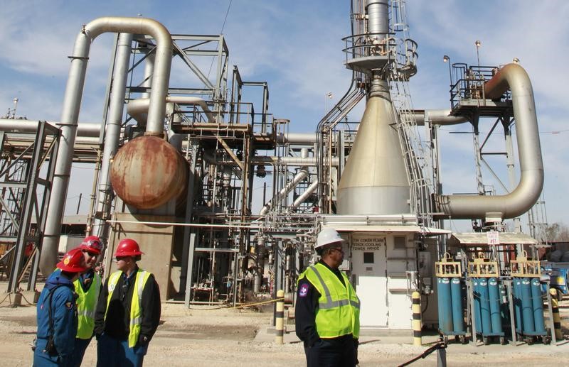 © Reuters. Refinery workers stand in front of the coker flare stack cooling tower after a press conference inside the LyondellBasell oil refinery in Houston