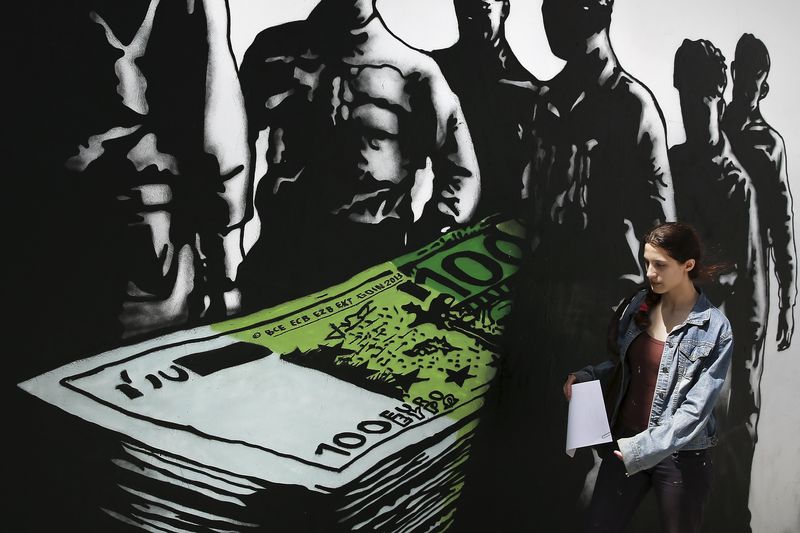 © Reuters. A woman makes her way past graffiti "Death of euros" made by French street artist Goin in Athens