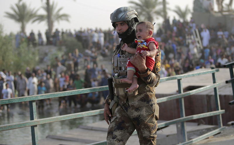 © Reuters. Soldado iraquiano leva menino de Ramadi desabrigado nos arredores de Bagdá