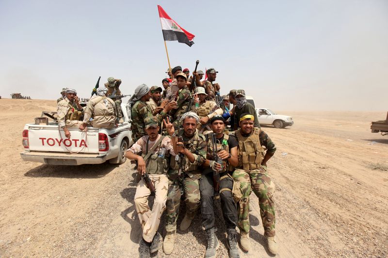 © Reuters. Iraq's Shi'ite paramilitaries ride in military vehicles in Nibai