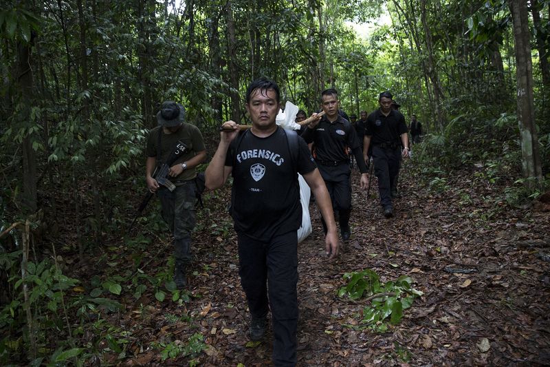 © Reuters. Members of a police forensic team carry a body bag with human remains dug from the grave near the abandoned human trafficking camp in the jungle close the Thailand border at Bukit Wang Burma in northern Malaysia