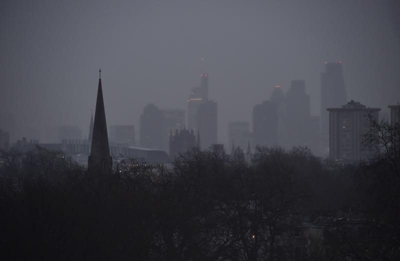 © Reuters. City of London financial district skyscrapers are seen behind a church spire at dawn in London