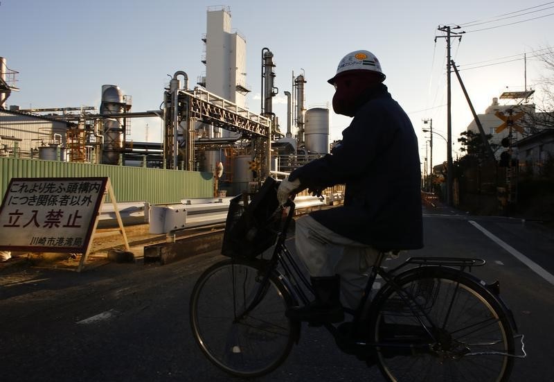 © Reuters. A worker cycles past a petro-industrial complex in Kawasaki near Tokyo