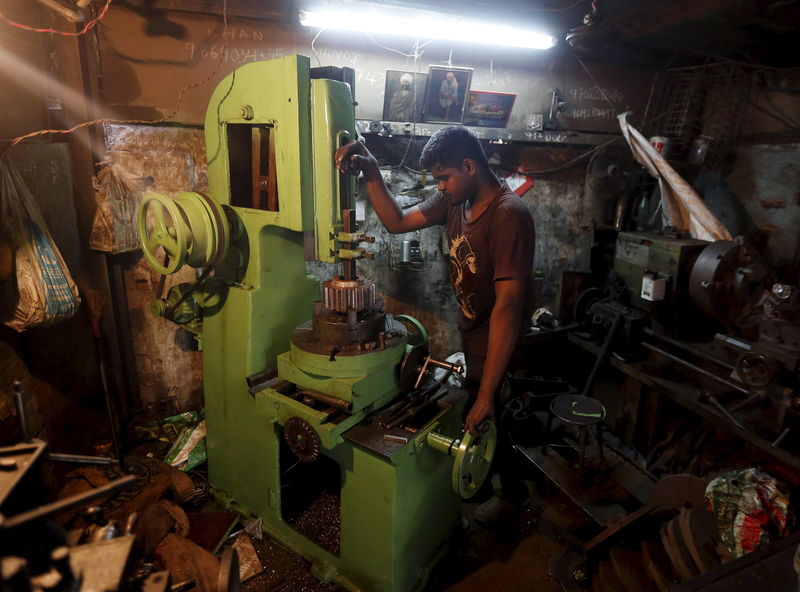 © Reuters. Worker operates a slotting machine as he makes keyways on gears at a workshop in Mumbai, India