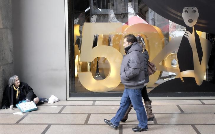 © Reuters. A couple strolls in front a shop during sales in downtown Milan