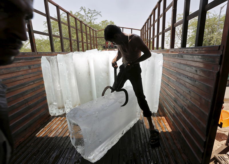© Reuters. Trabalhador corta gelo para resfriamento de alimentos em mercado na Índia
