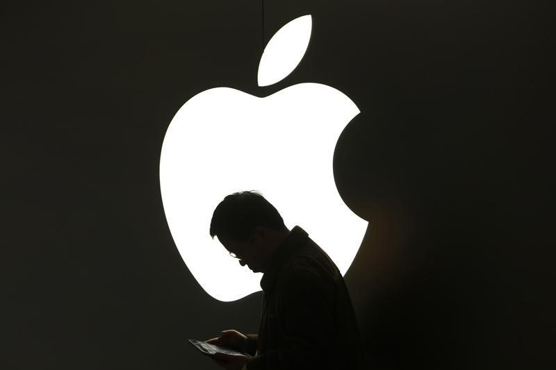 © Reuters. A man looks at his Apple iPad in front an Apple logo outside an Apple store in downtown Shanghai