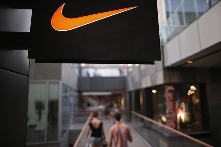 © Reuters. People walks past a Nike shop under the company logo at the Sanlitun shopping area in central Beijing